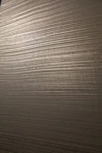 Eine elegante Wand zeigt die metallische Struktur von ATHOS-Weissgold für kreative Wandgestaltung im Wohnzimmer.