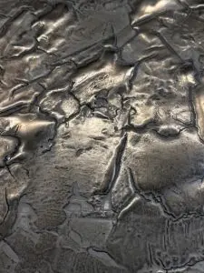 Die Nahaufnahme zeigt eine kunstvoll strukturierte Oberfläche mit metallischem Glanz, ideal für kreative Wandgestaltung.
