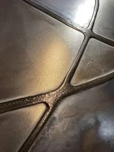 Eine stilvolle Wandfläche zeigt metallische Spachteltechnik mit flüssigem Metall, ideal für kreative Möbelgestaltung. Rezept: Unikat
