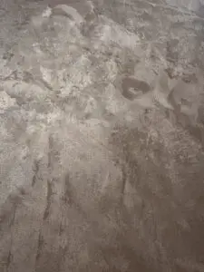 Die Wand zeigt eine MONROE-Effeckt-Wandbeschichtung mit metallischem Glanz, ideal für kreative Wandgestaltung im Wohnzimmer.