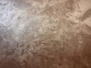 Die Wand zeigt eine MONROE-Effektbeschichtung mit metallischem Glanz, ideal für kreative Wohnzimmer-Wandgestaltung von Einhornwerke.