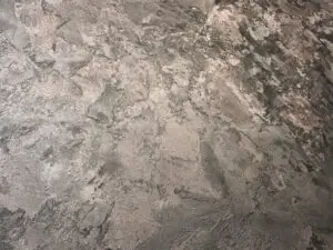 Die Wand zeigt eine MONROE-Wandbeschichtung mit metallischem Glanz, ideal für kreative Wohnzimmer-Wandgestaltung.