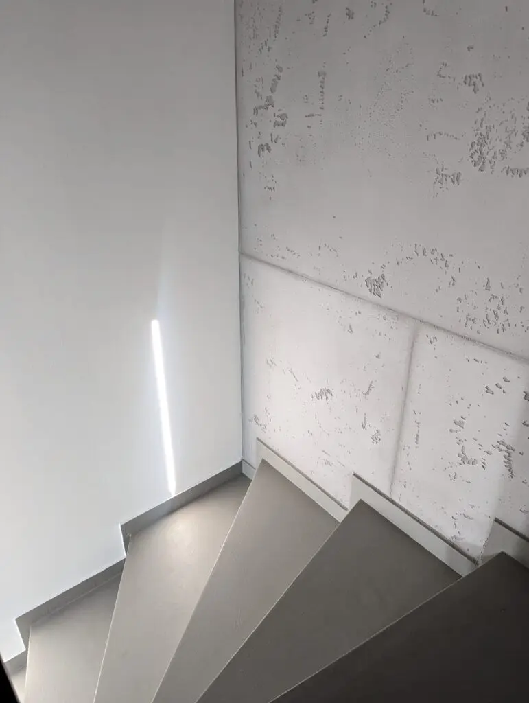 Die fugenlose Treppe führt an künstlerisch gespachtelten Wänden im Betonoptik-Treppenhaus von Einhornwerke vorbei.