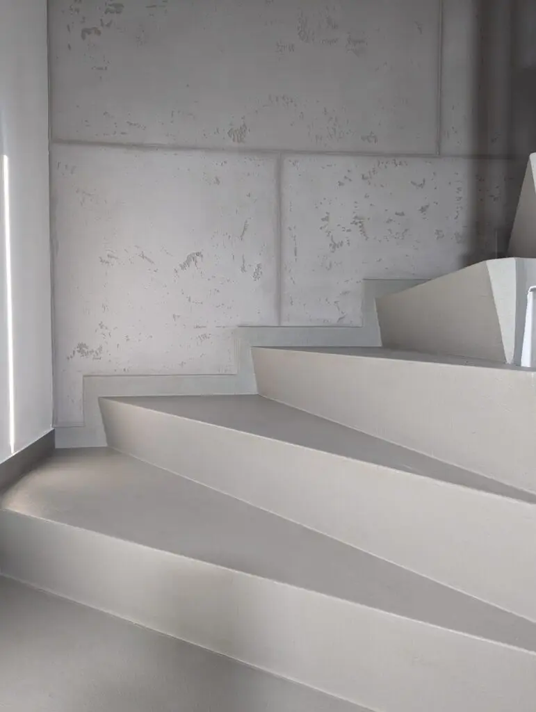 Eine fugenlos gespachtelte Treppe in Betonoptik zeigt moderne Wandgestaltung im Treppenhaus.