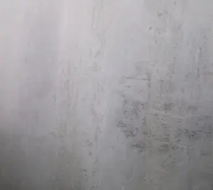 Die Wand zeigt eine natürliche Struktur mit Oberflaeche-STUCCORINO Alt-Berlin in dezenten Grautönen für kreative Wandgestaltung.