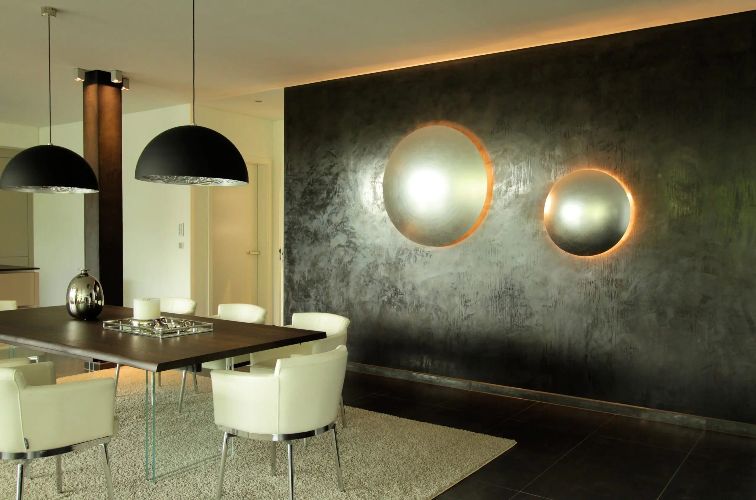 Ein stilvolles Wohnzimmer mit moderner Wandgestaltung in dunklem Kalk-Marmor-putz und leuchtenden Akzenten von Einhornwerke.
