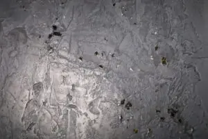 Die Wand zeigt eine kreative Streichputzstruktur mit schimmerndem Goldglimmer und Black Pearl von Einhornwerke. Rezept: STUCCORINO ® 0,5 Farbton 3020 + Goldglimmer + Black Pearl Glimmer mittel + WAX-Creme