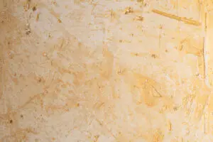 Eine Wand zeigt eine edle Oberflächenstruktur in Pariser-Goldbruch mit Kalkputz, ideal für kreative Wandgestaltung im Wohnzimmer.