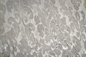 Eine Wand zeigt ein elegantes Florales Muster in Naturtönen, ideal für kreative Wandgestaltung. Rezept: STUCCORINO ® Struktur STUCCORINO ® 0,1 Farbton Natur + Imprägnierung + Shabby Finish - schwarz