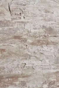 Die Wand zeigt eine einzigartige, strukturierte Oberfläche im Shabby-Finish, ideal für kreative Wandgestaltung im Wohnzimmer. Rezept: STUCCORINO ® Unikat 1040 + 0802 STUCCORINO + Natur + Shabby Finish