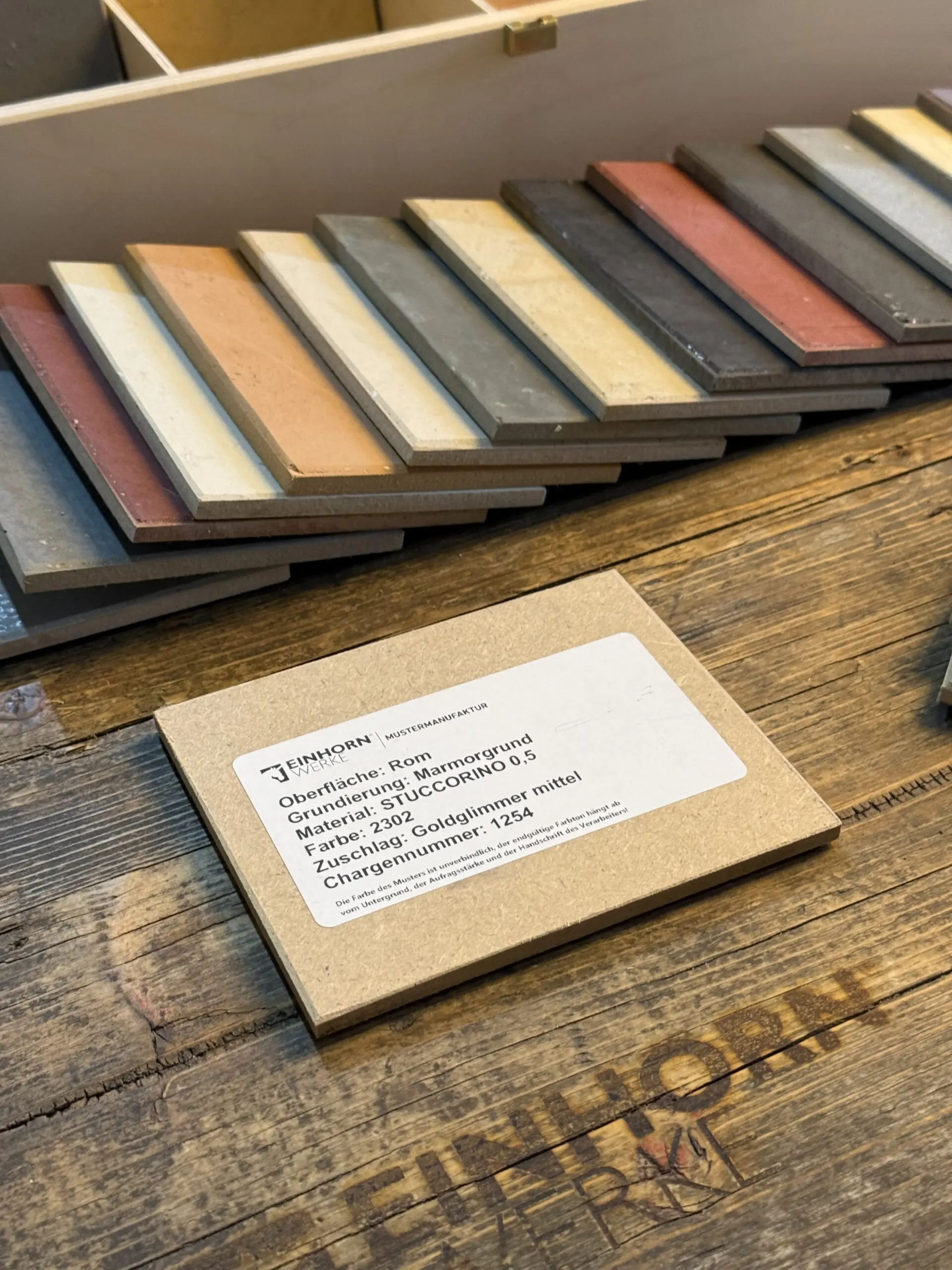 Eine STUCCORINO-Musterbox von Einhornwerke zeigt vielfältige Farben für kreative Wandgestaltung im Wohnzimmer.