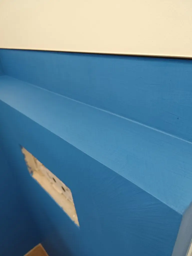 Blau beschichtete Wand mit Ablage und Revisionsöffnung im Bad während der Renovierung