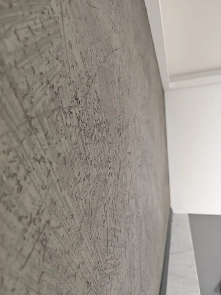 Grau gespachtelte Wand mit kreuzweise gezogener Kratzstruktur in Betonoptik, seitlich fotografiert