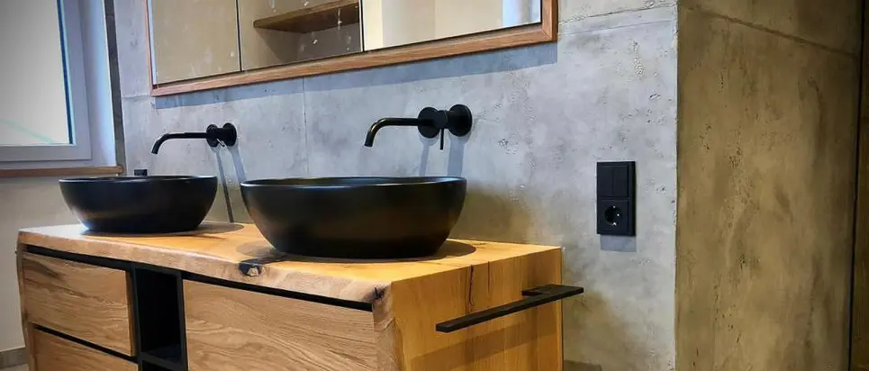 Ein Badezimmer mit Betonoptik-Wandgestaltung und schwarzem Waschbecken von Einhornwerke strahlt moderne Eleganz aus.