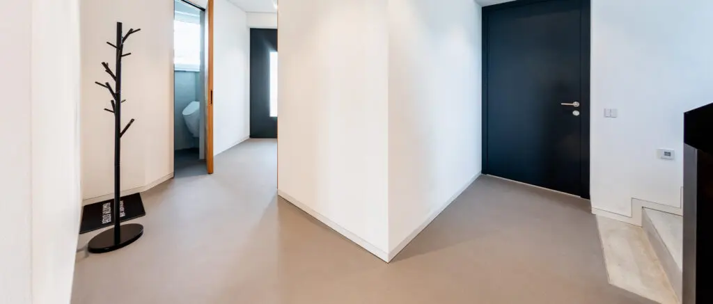 Ein moderner Flur mit Betonoptikboden-Spachtelboden und schlichter Wandgestaltung von Einhornwerke.
