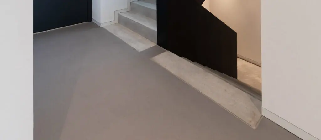 Eine moderne Treppe mit Bodenbeschichtung in Betonoptik verbindet stilvoll zwei Etagen durch Spachteltechnik von Einhornwerke.