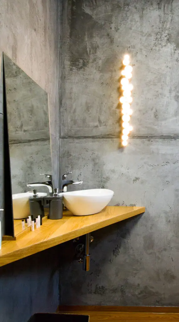 Ein stilvolles Badezimmer zeigt eine kreative Betonoptik-Wandgestaltung von Einhornwerke mit modernem Waschbecken.