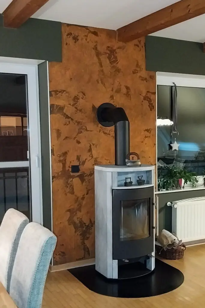 Kaminofen vor Wandfläche in rostbrauner Spachteltechnik mit fleckiger Struktur