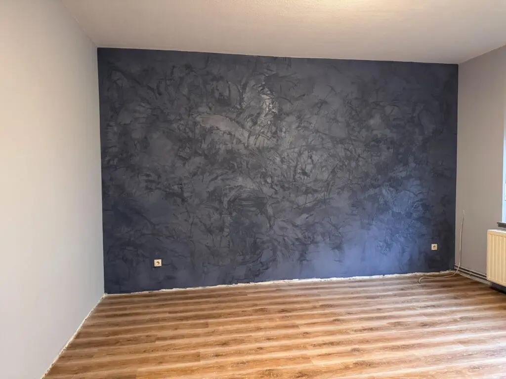 Akzentwand in dunkelblauer Spachteltechnik mit Wischstruktur über Holzdielenboden in leerem Raum