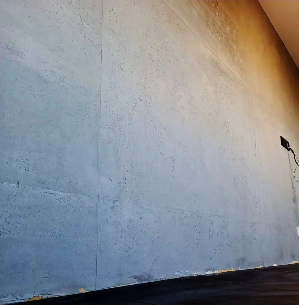 Große graue Wand in Betonoptik mit Schalungsfugen und Porenstruktur bis zur Decke