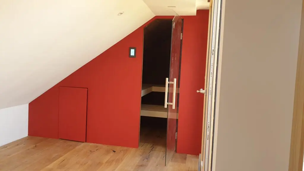Ein modernes Wohnzimmer mit roter Wandgestaltung und Holzfußboden schafft eine einladende Atmosphäre | © Einhornwerke.