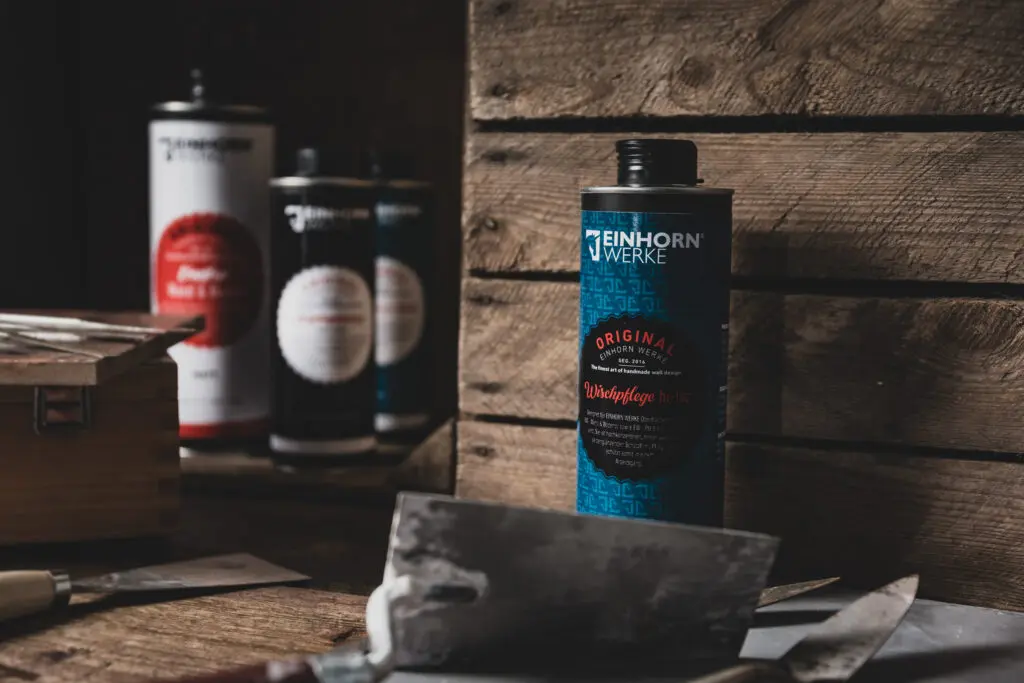 Verschiedene Produkte von Einhorn Werke auf Holzregal für Wandgestaltung und fugenloses Bad in Betonoptik. | © Einhorn Werke