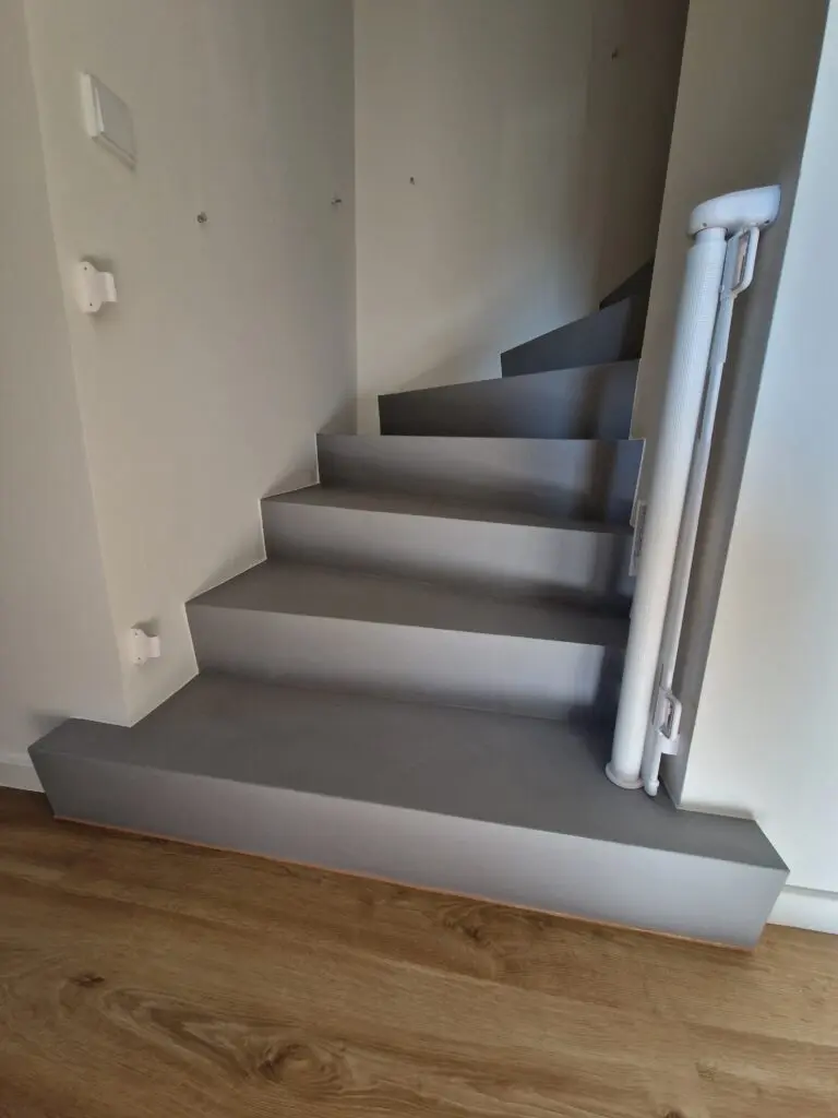 Gewendelte Treppe mit grauen Microzement-Stufen, Antritt auf Holzboden