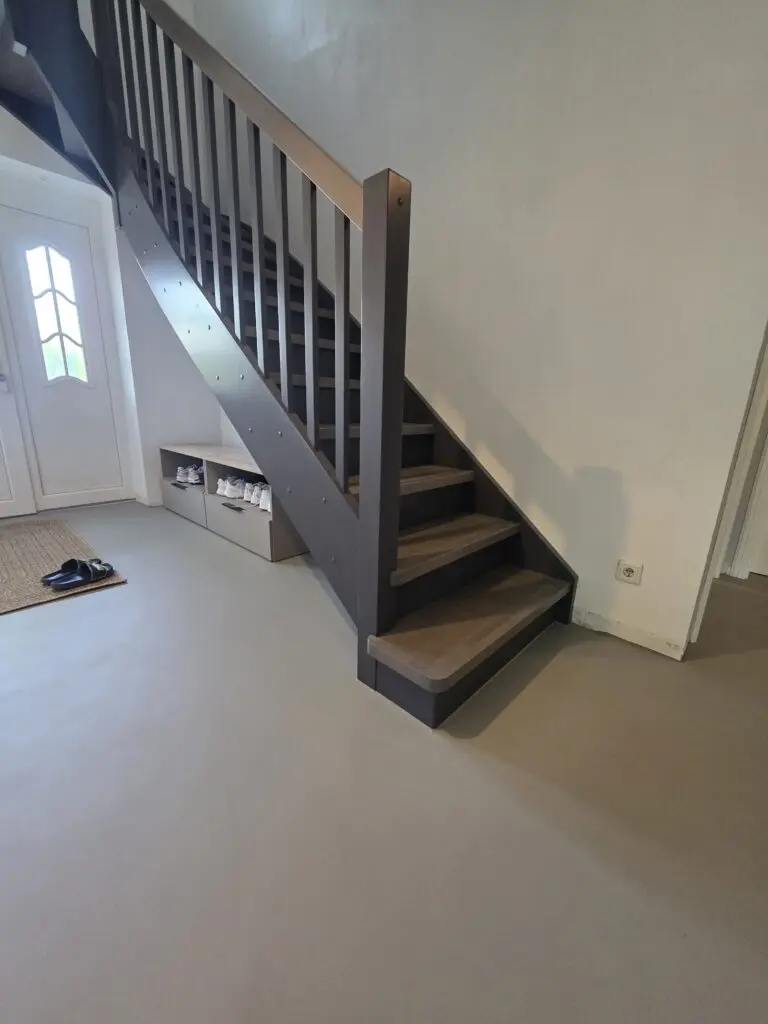 Dunkelgraue Holztreppe im Eingangsbereich auf hellgrauem fugenlosem Microzementboden