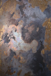 Eine kunstvolle Wandgestaltung zeigt die Patina von ATHOS-Messing in fließenden, metallischen Farben.