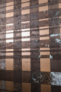 Die Wandgestaltung zeigt ein geometrisches Muster in rosegold und braun, ideal für modernes Wohnzimmerdesign von Einhornwerke.