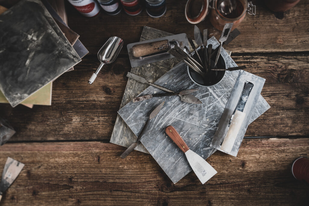 Ein Tisch voller Werkzeuge und Materialien für kreative Wandgestaltung von Einhorn Werke liegt auf rustikalem Holz.