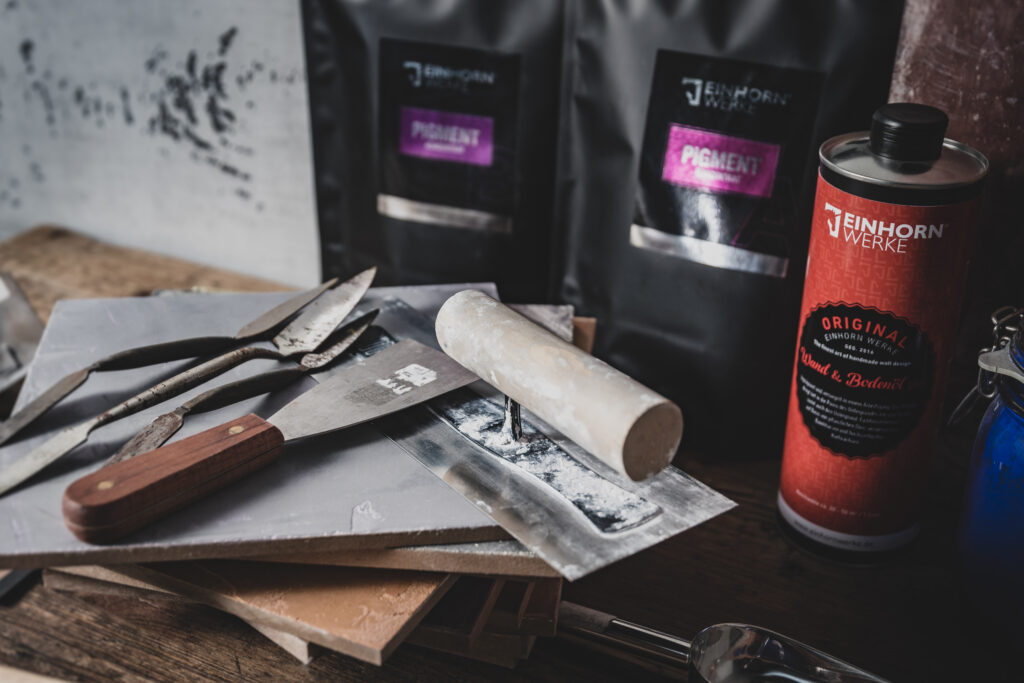 Ein Tisch mit Werkzeugen und Materialien von Einhornwerke zeigt die Vorbereitung für eine kreative Wandgestaltung.