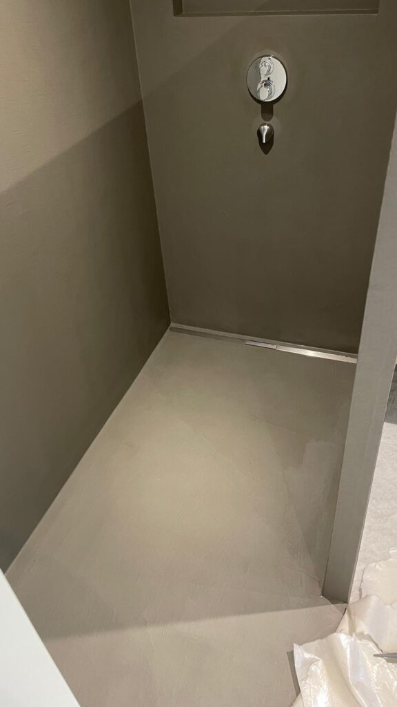 Ein modernes, fugenloses Badezimmer zeigt eine glatte Wandgestaltung als Alternative zu Fliesen.