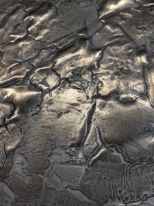 Die Nahaufnahme zeigt eine kunstvoll strukturierte Oberfläche mit metallischem Glanz, ideal für kreative Wandgestaltung.