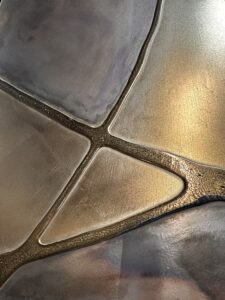 Eine kunstvolle Oberfläche mit Echtmetall-Spachtel zeigt elegante, geometrische Muster für moderne Oberflächen. Rezept: Unikat.