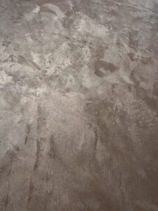 Die Wand zeigt eine MONROE-Effeckt-Wandbeschichtung mit metallischem Glanz, ideal für kreative Wandgestaltung im Wohnzimmer.
