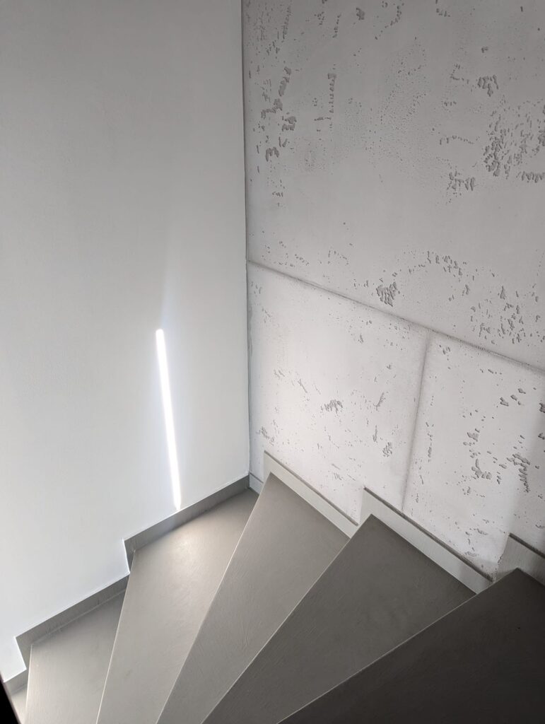 Die fugenlose Treppe führt an künstlerisch gespachtelten Wänden im Betonoptik-Treppenhaus von Einhornwerke vorbei.