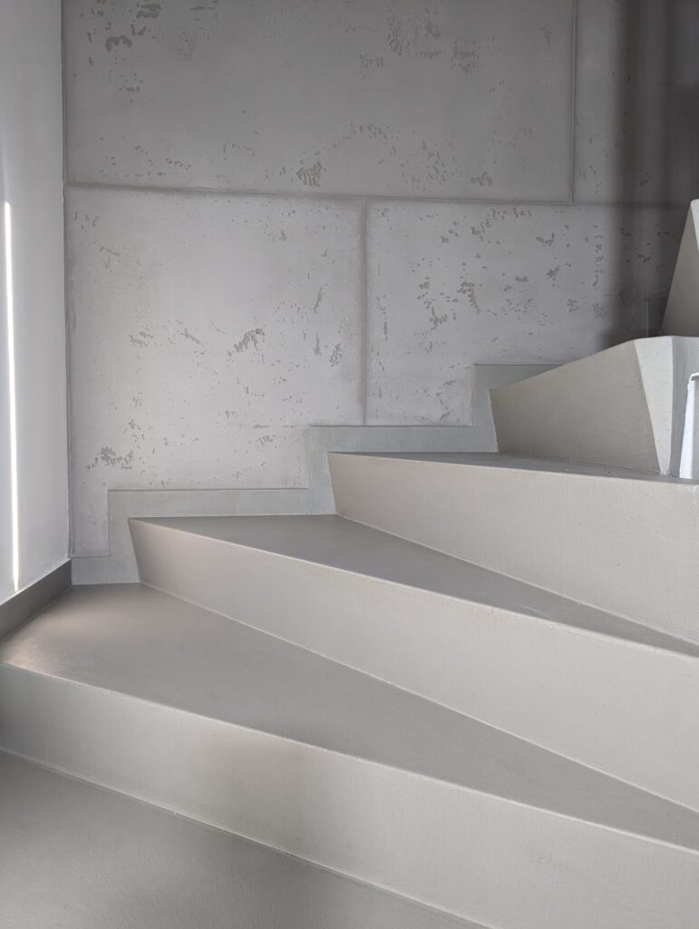 Eine fugenlos gespachtelte Treppe in Betonoptik zeigt moderne Wandgestaltung im Treppenhaus.