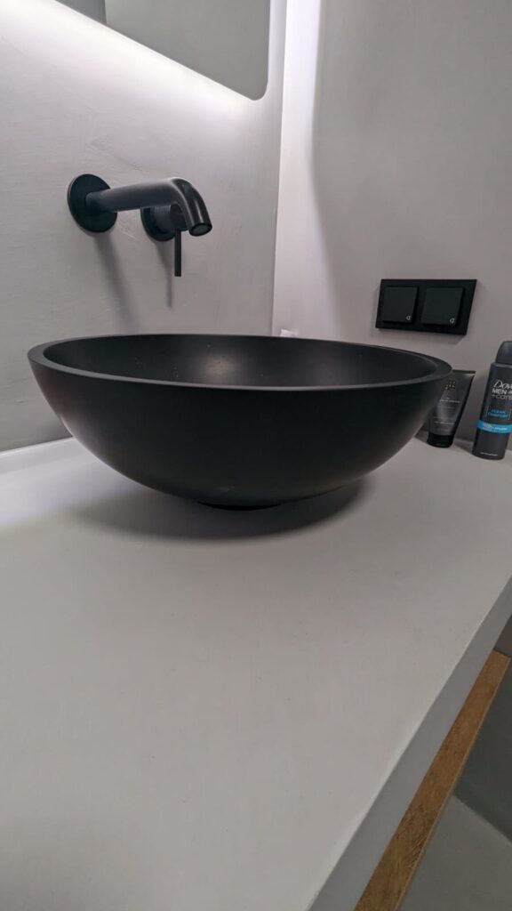 Ein modernes Badezimmer ohne Fliesen zeigt ein fugenloses Waschbecken-Design mit stilvoller Wandgestaltung.