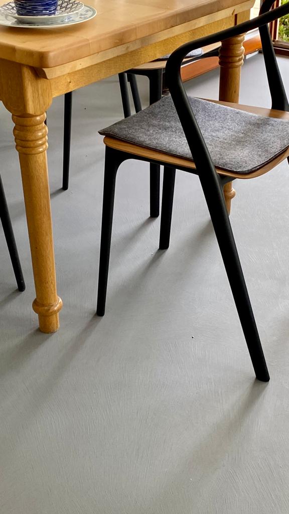 Ein Holztisch und Stuhl stehen auf einem glatten Boden, ideal für kreative Wandgestaltung im Wohnzimmer von Einhornwerke.