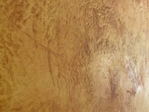 Die Wand zeigt eine kunstvolle Struktur in warmen Erdtönen, gestaltet mit Oberflaeche-STUCCORINO für kreative Wandgestaltung.