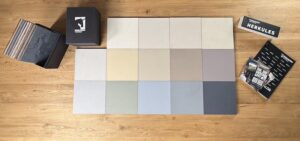 Eine „Best-of…-HERKULES-Musterbox“ zeigt verschiedene Farben für kreative Wandgestaltung auf einem Holzboden.