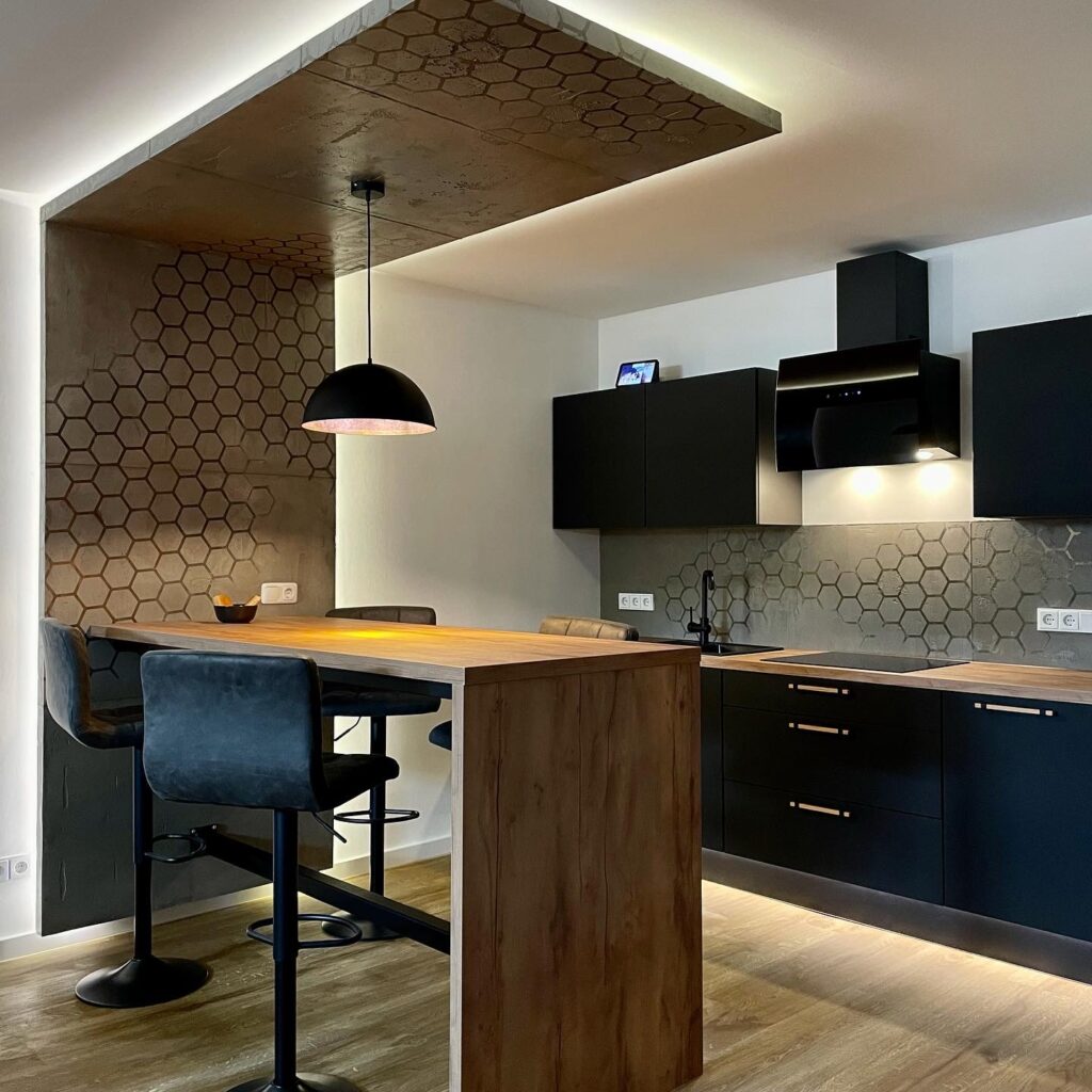 Eine moderne Küche mit hexagonaler Wandgestaltung und stilvollen, schwarzen Schränken schafft ein elegantes Ambiente.