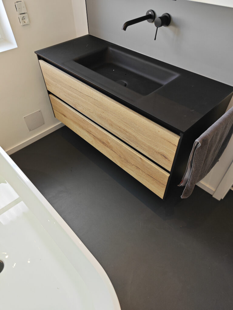 Ein stilvolles Badezimmer mit modernem Waschbecken und Microzement-Boden vom Hersteller Einhorn Werke.