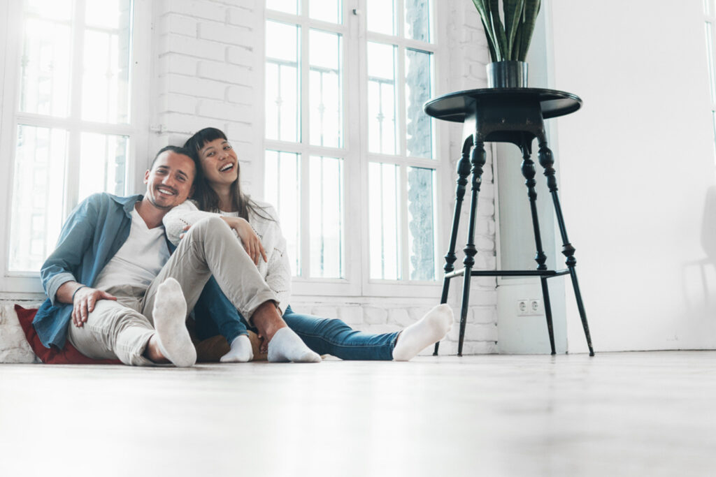 Ein Paar sitzt entspannt auf dem Microzement Boden in einem stilvoll gestalteten Wohnzimmer vom Hersteller Einhorn Werke.