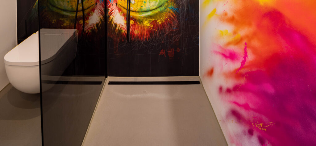 Ein modernes Badezimmer mit farbenfroher Wandgestaltung und glattem Boden zeigt kreative Akzente vom Microzement Hersteller Einhornwerke.