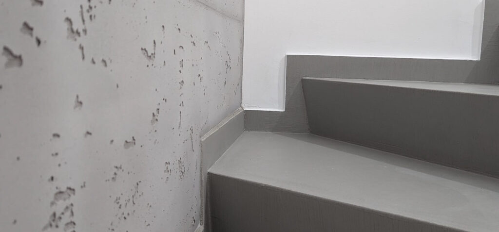Ein modernes Treppenhaus zeigt eine stilvolle Wandgestaltung in Betonoptik von Einhornwerke.